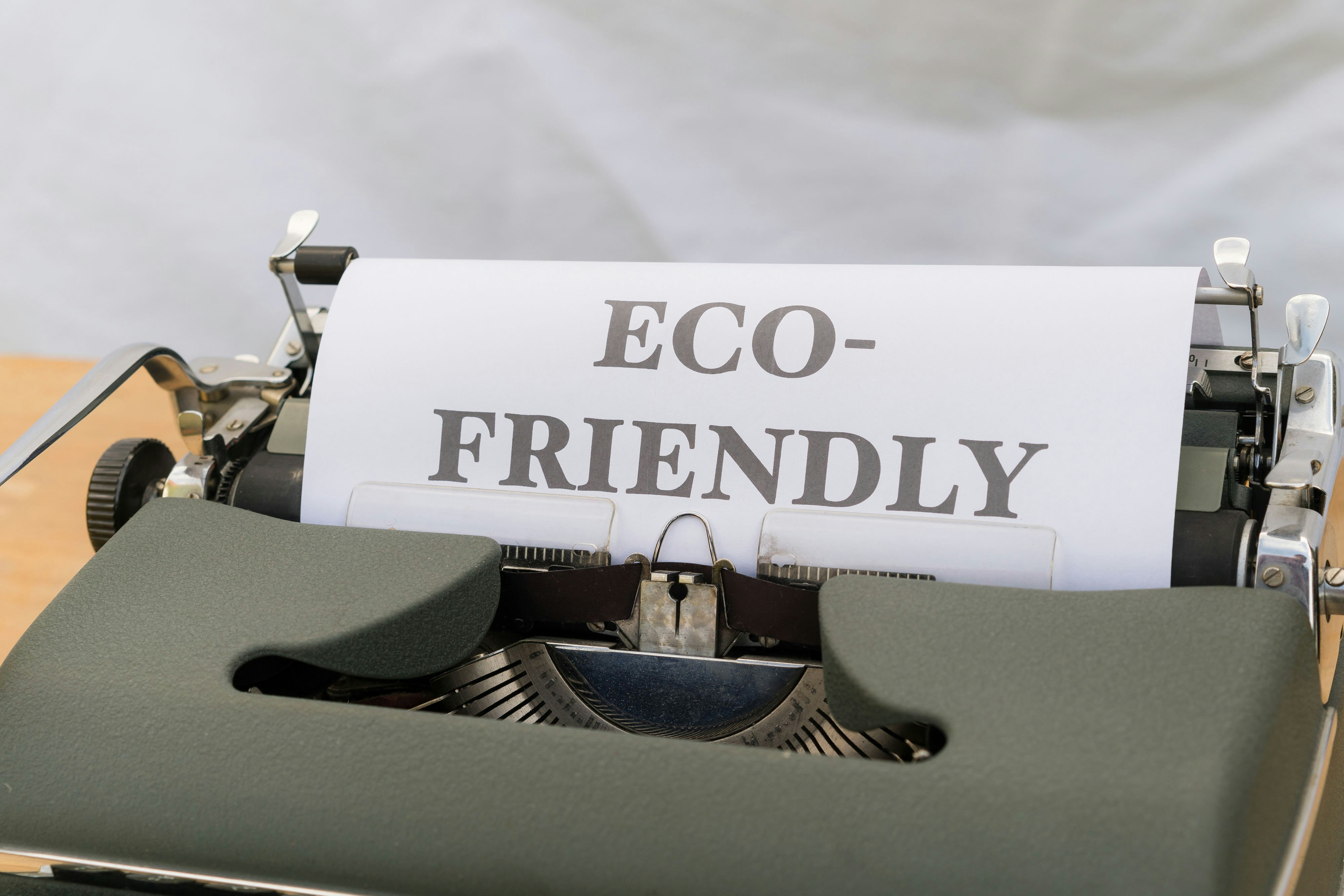 a close up of a typewriter with a paper that reads eco – friendly